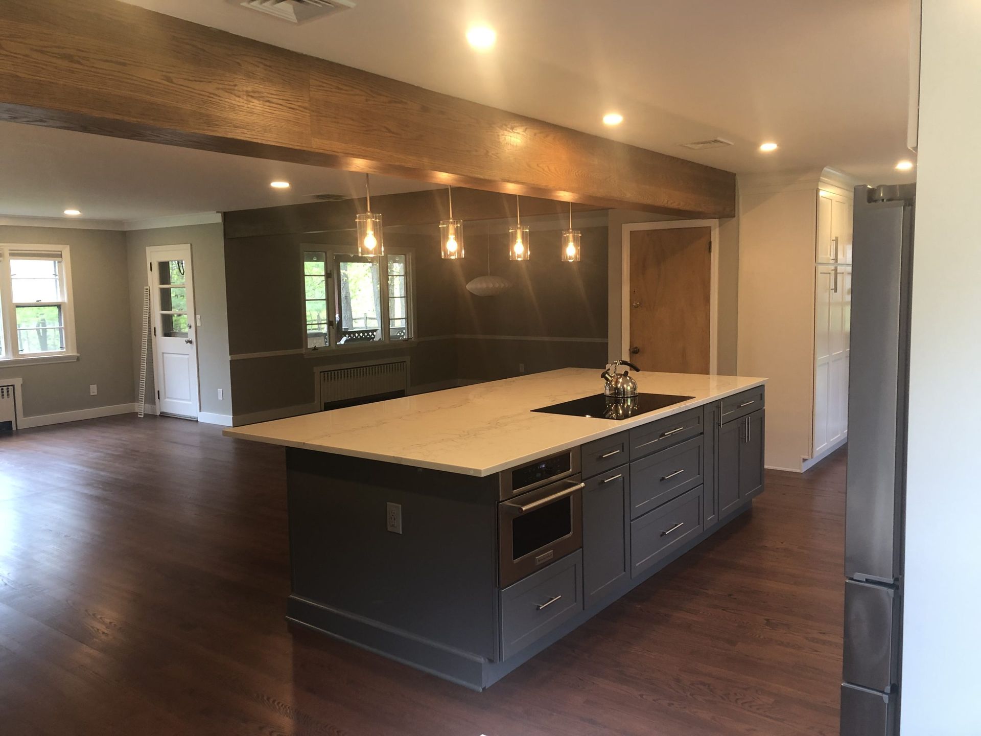 Modern open-plan kitchen with dark cabinets, light island, wood floors, and recessed lighting