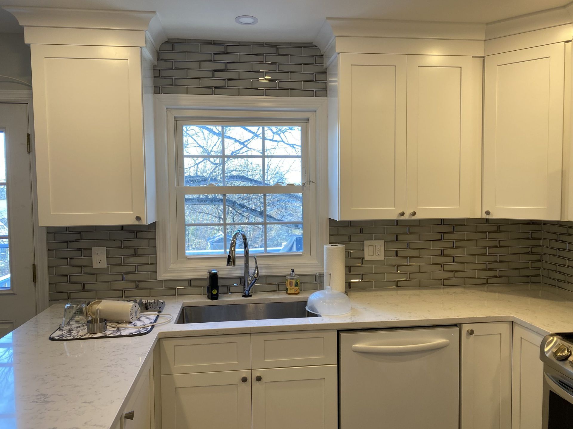 Bright kitchen with white cabinets, stone backsplash, and a window over the sink