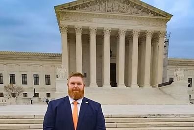 Man in suit and tie stands in front of the U.S. Supreme Court building.
