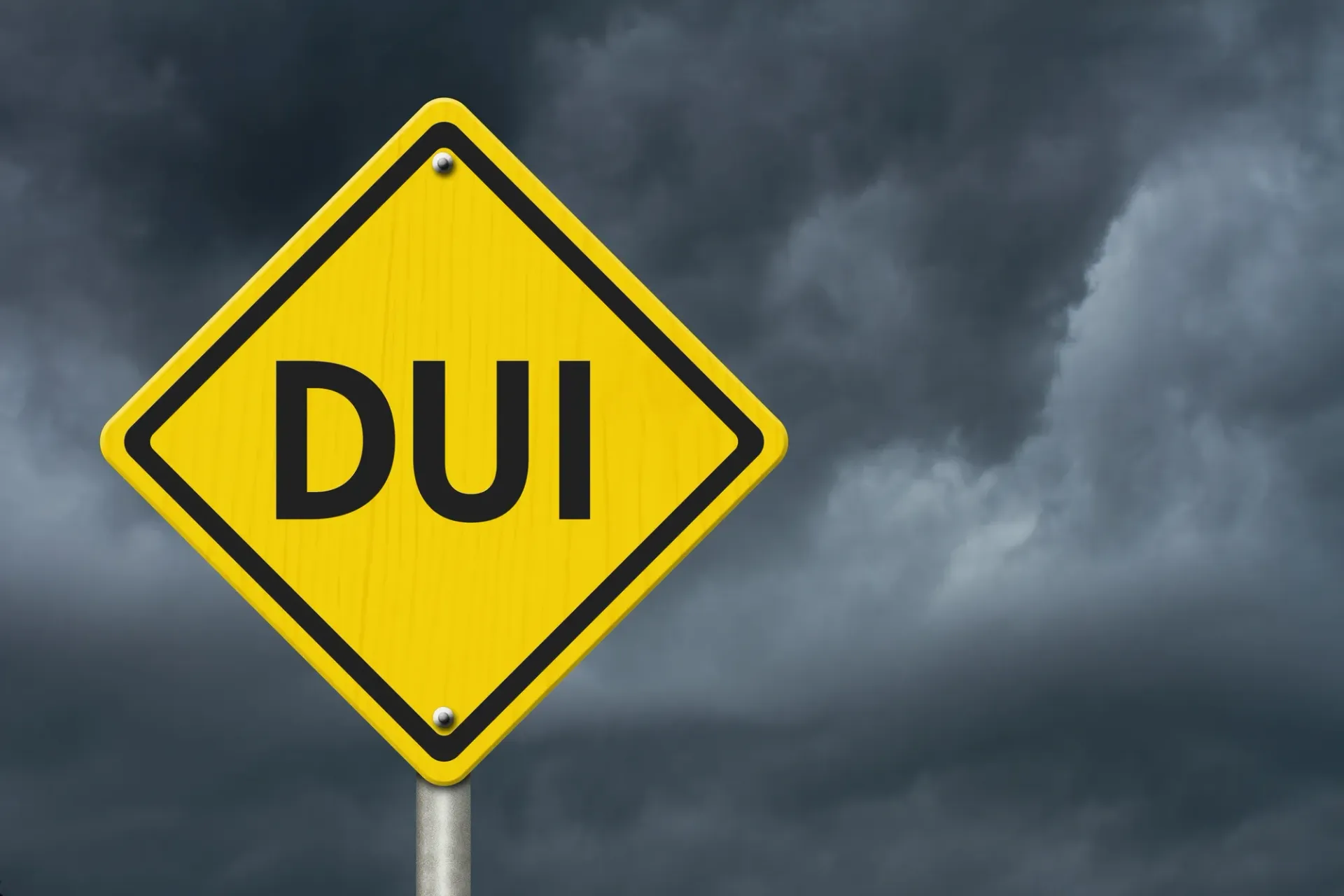Yellow diamond road sign, DUI in black letters, against a dark, stormy sky.