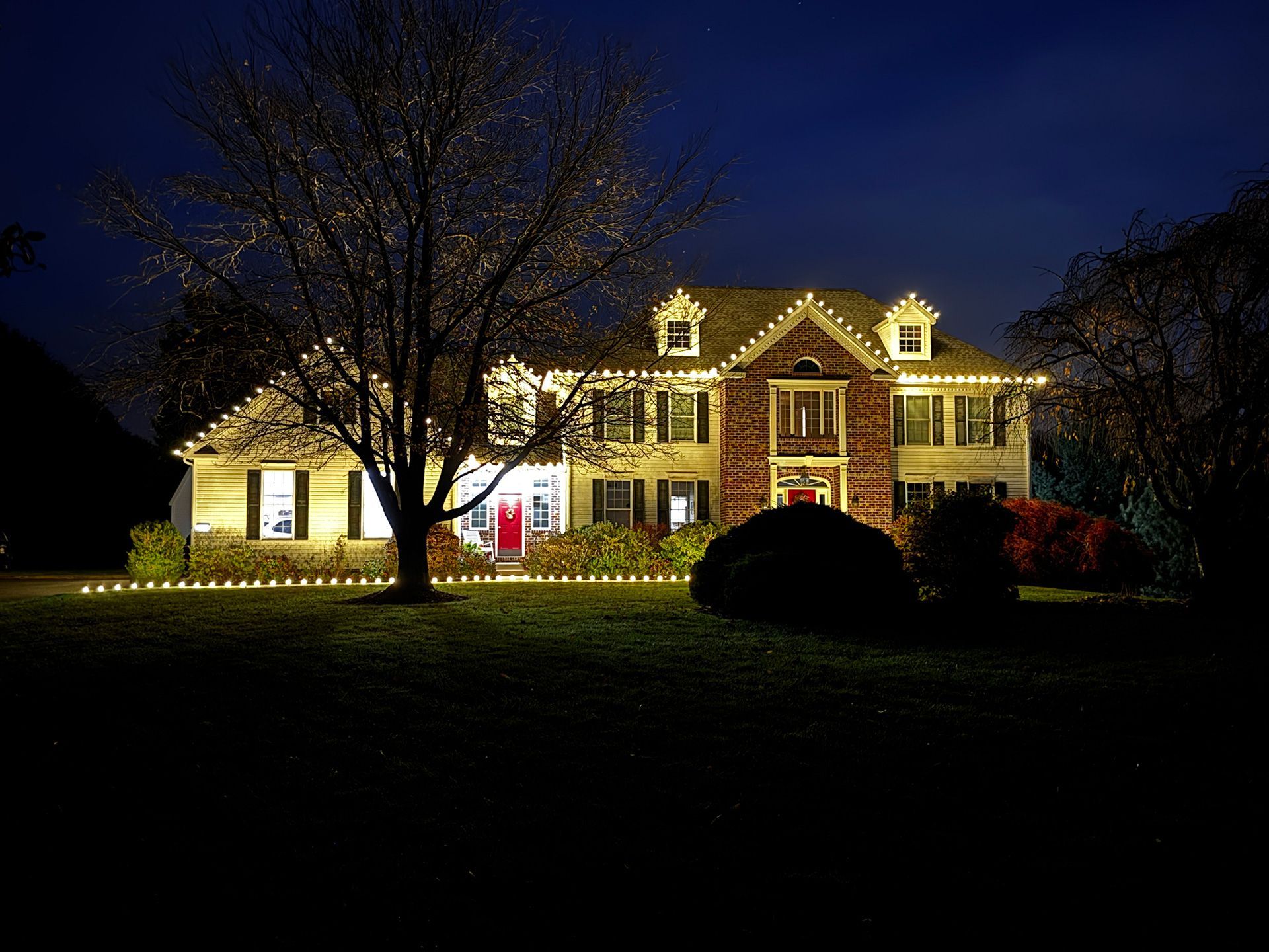 The house at night is decorated with white lights for the holidays.