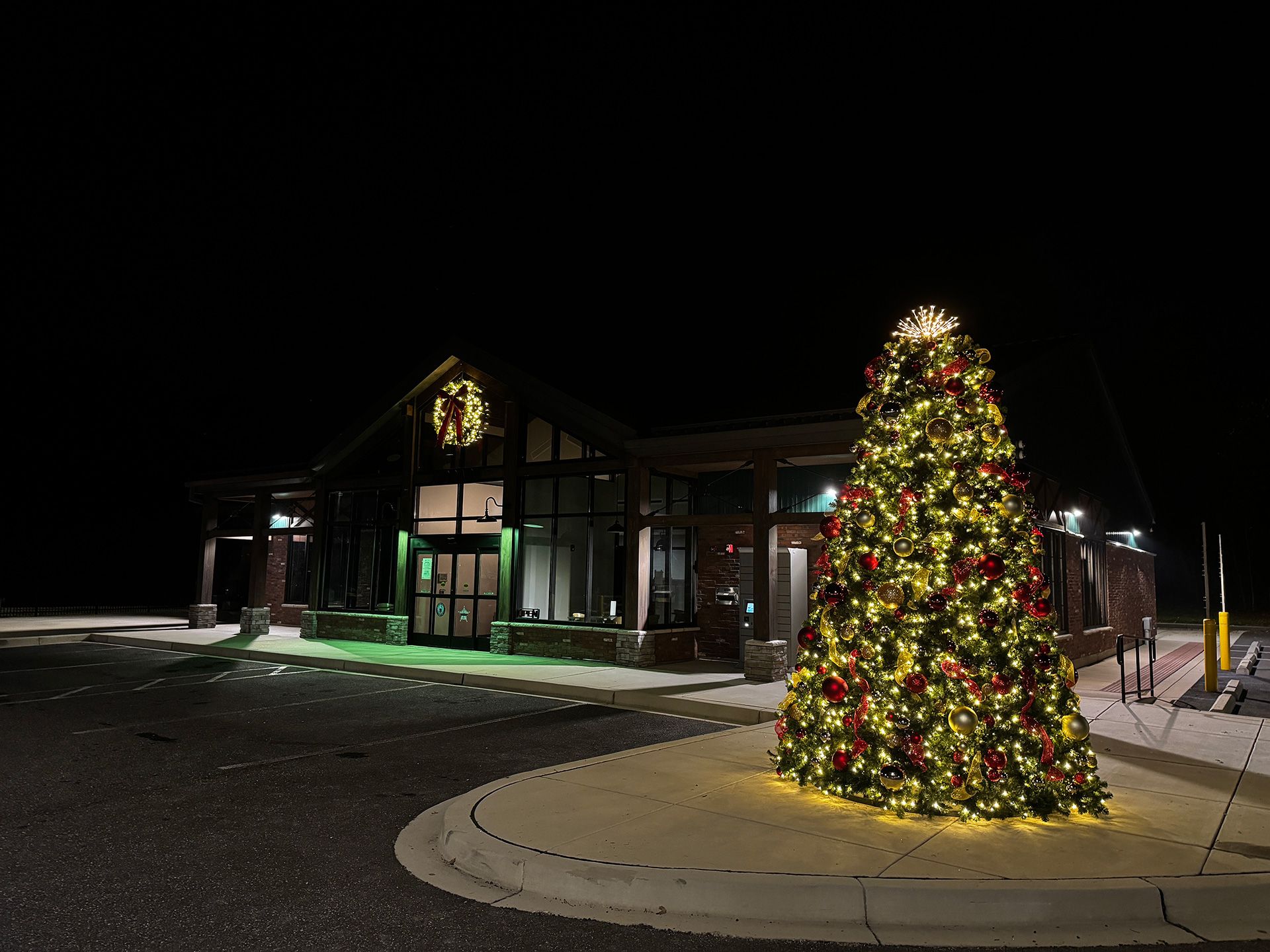 Night scene of a building with a large Christmas tree lit with golden lights and red ornaments.