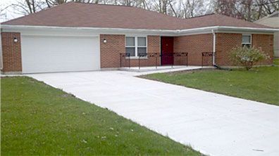 A brick house with a white driveway leading to it