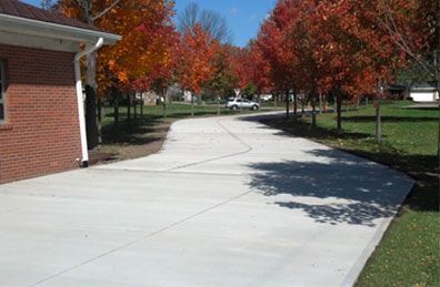 A brick house with a concrete driveway leading to it.