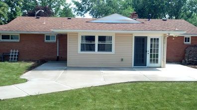 The back of a brick house with a patio in front of it.