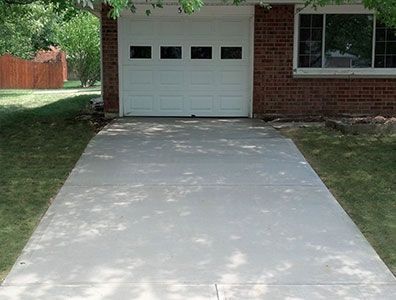 A brick house with a white garage door and a concrete driveway leading to it.