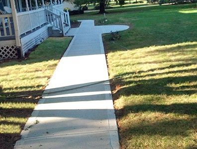 A concrete walkway leading to a house on a sunny day