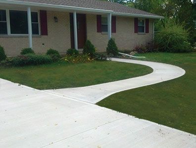 A brick house with a concrete walkway leading to it
