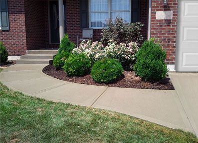 A brick house with a concrete walkway leading to the front door.