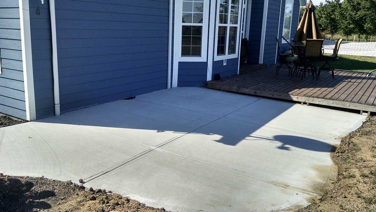 A blue house with a concrete patio in front of it.