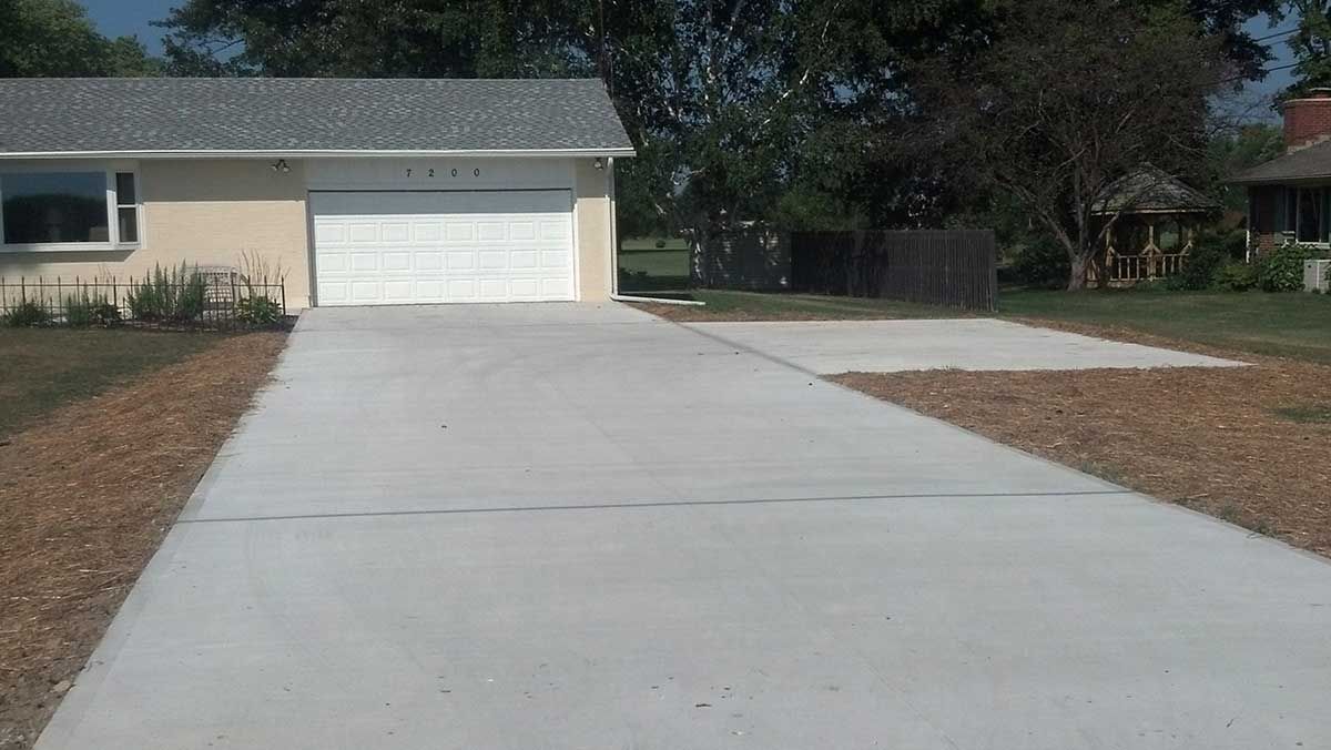 A concrete driveway leading to a house with a garage.