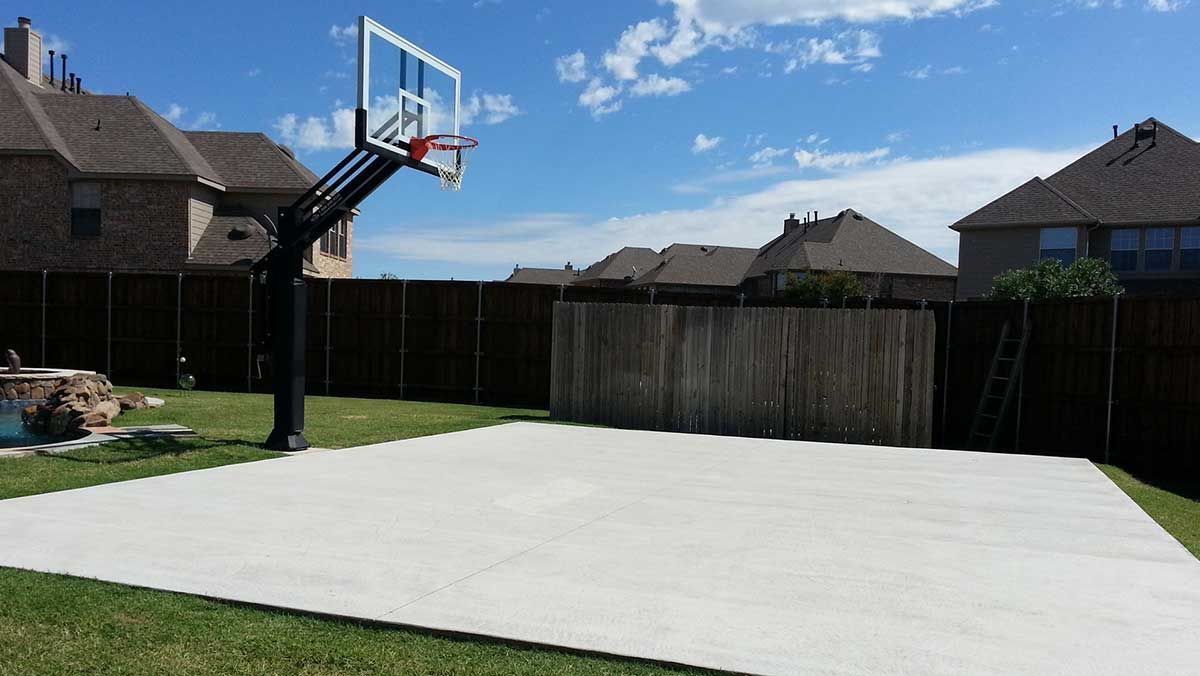 There is a basketball hoop in the backyard of a house.