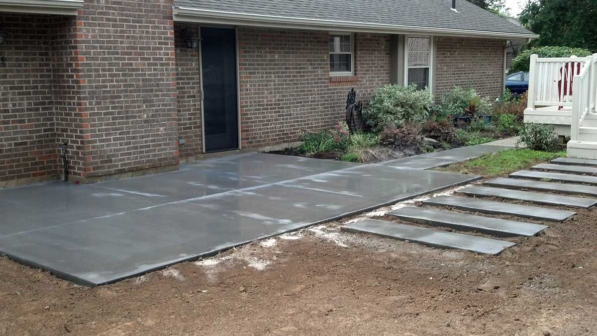 A brick house with a concrete driveway and steps leading to it.