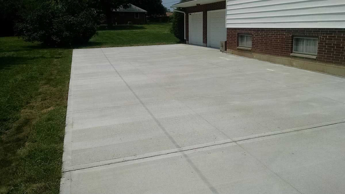 A concrete driveway leading to a brick house.