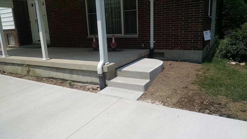 A brick house with a concrete porch and steps.