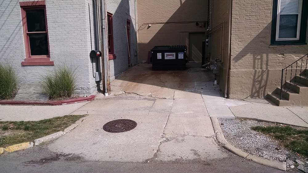 A narrow alleyway between two buildings with a trash can in the middle