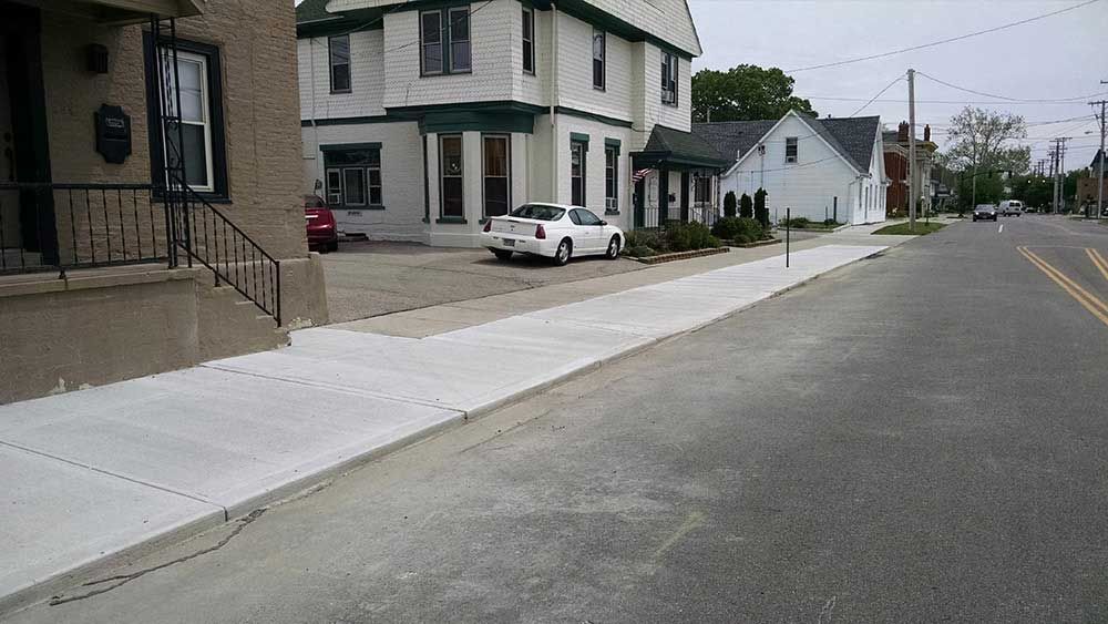 A white car is parked on the side of the road