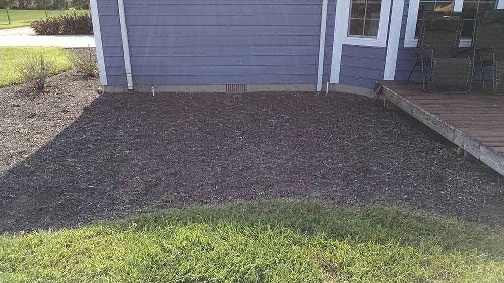 A blue house with a gravel driveway in front of it.