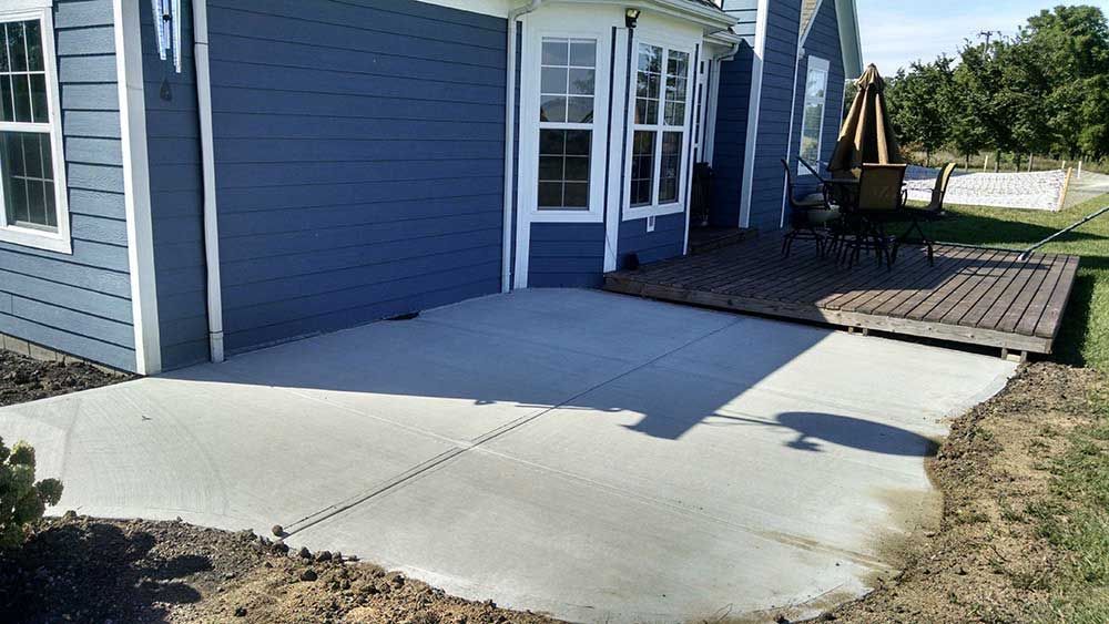A blue house with a concrete patio in front of it.