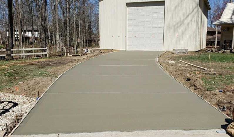 A concrete driveway is being built in front of a garage.
