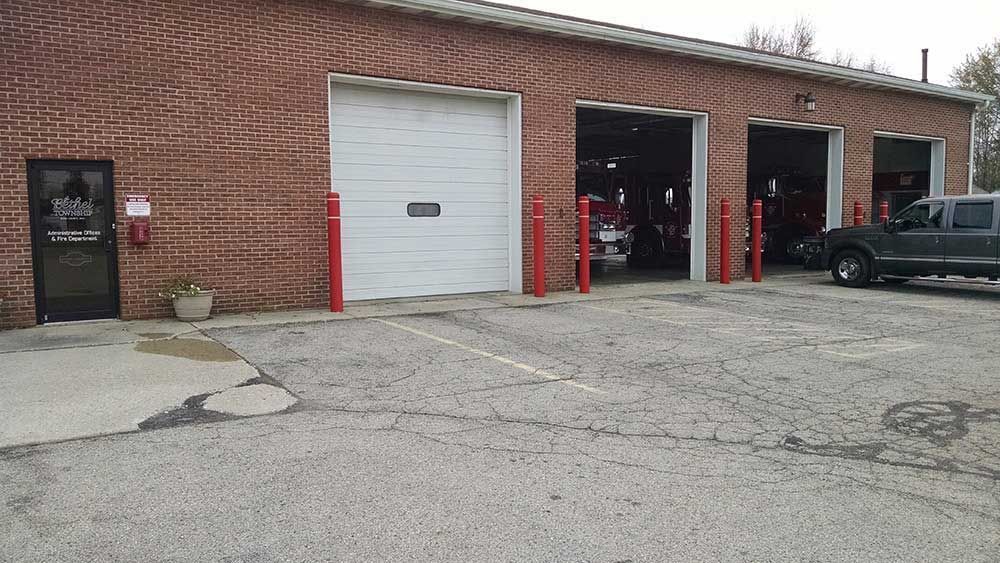 A brick building with three garage doors and a truck parked in front of it.