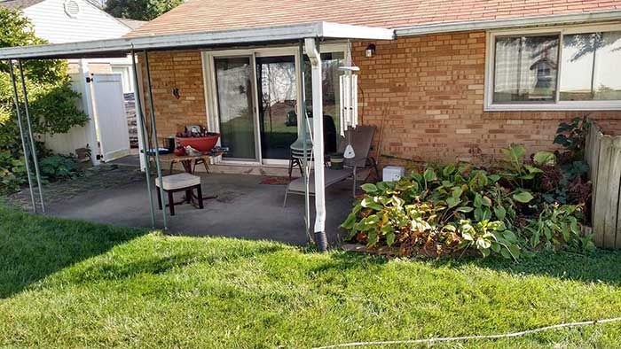 A brick house with a covered patio in the backyard.