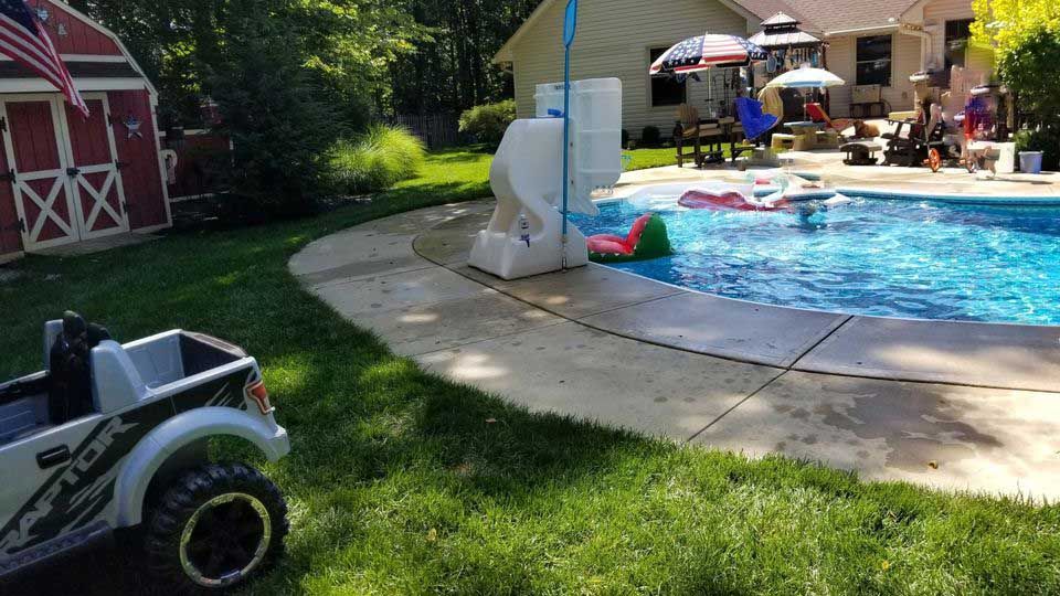 A toy truck is parked in front of a swimming pool.
