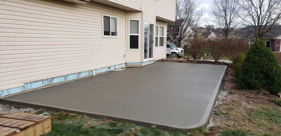 A concrete patio is being built in front of a house.