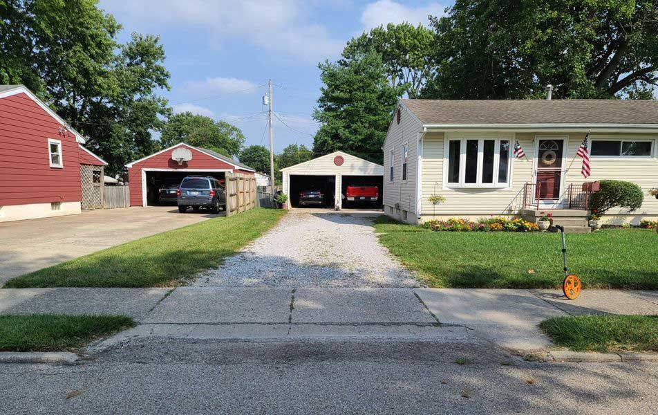 A driveway leading to a house with a car parked in front of it.