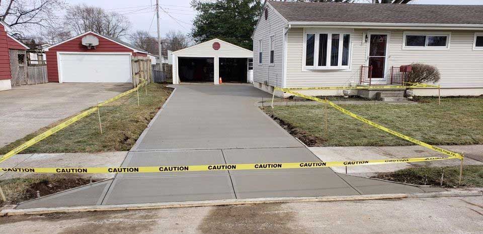 A concrete driveway is being built in front of a house