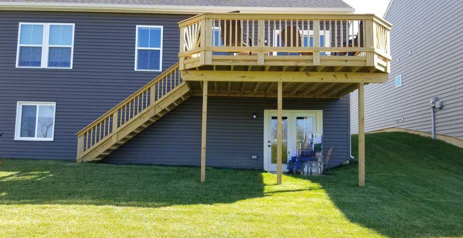 The back of a house with a wooden deck and stairs.