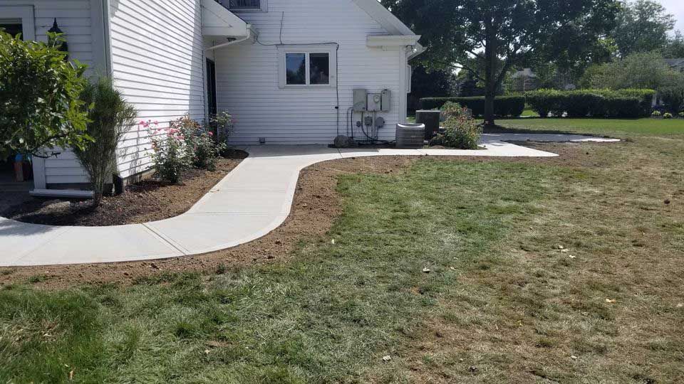 A white house with a concrete walkway leading to it.