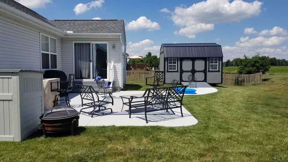 The backyard of a house with a patio and a shed.