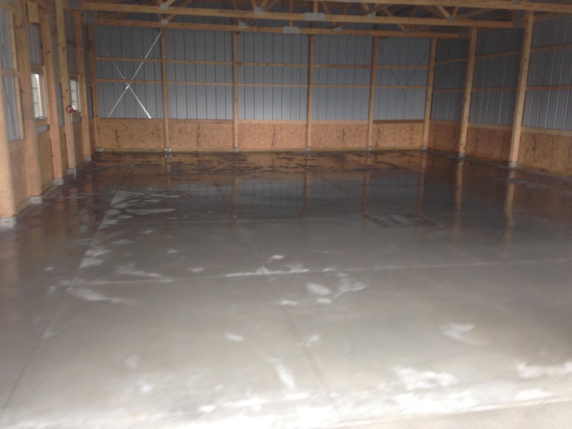 A large empty room with a concrete floor and wooden walls.