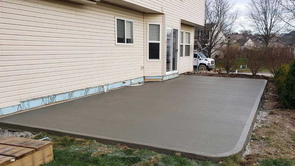 A concrete patio is being built in front of a house.