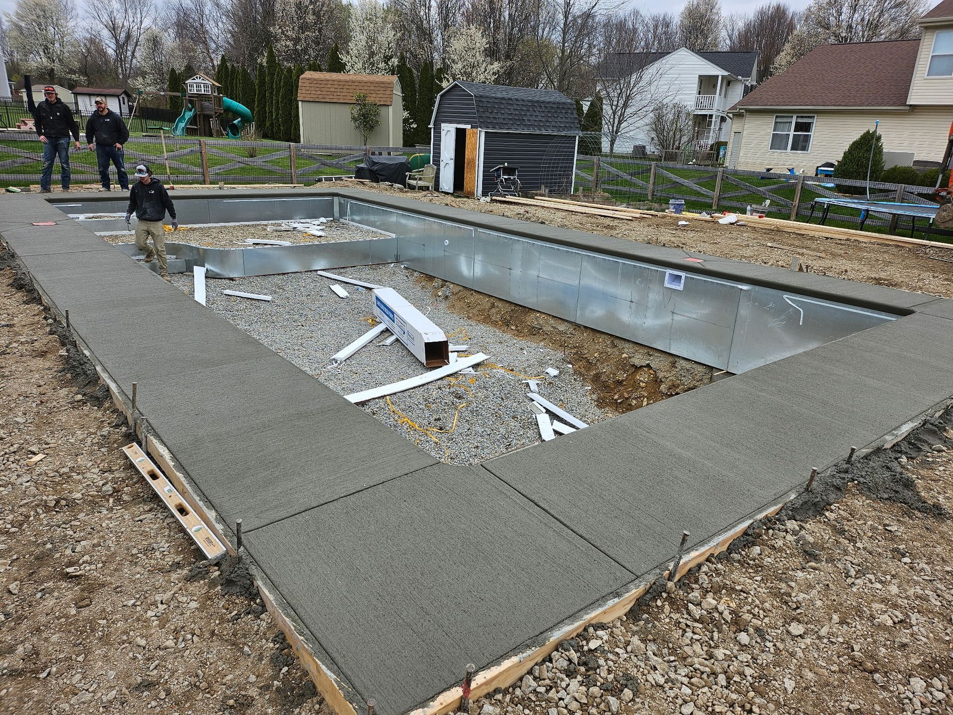 A swimming pool is being built in the backyard of a house.