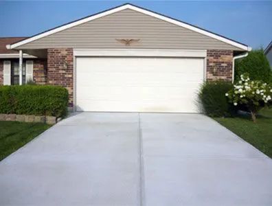 A house with a white garage door and a concrete driveway leading to it.
