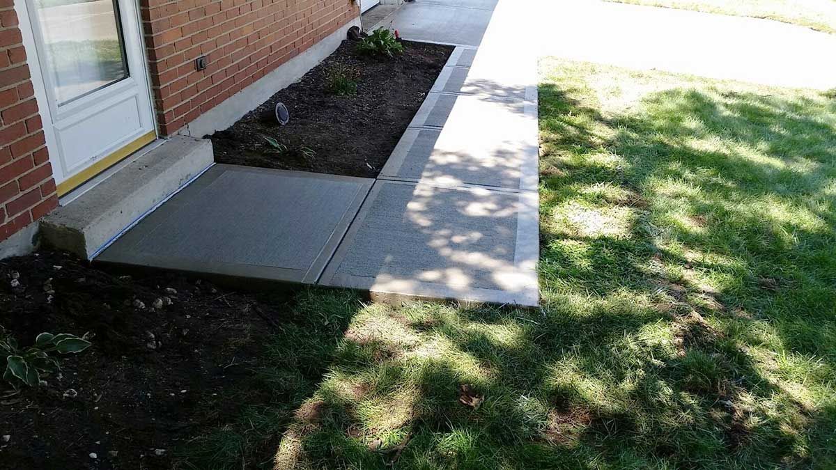 A brick house with a sidewalk in front of it.