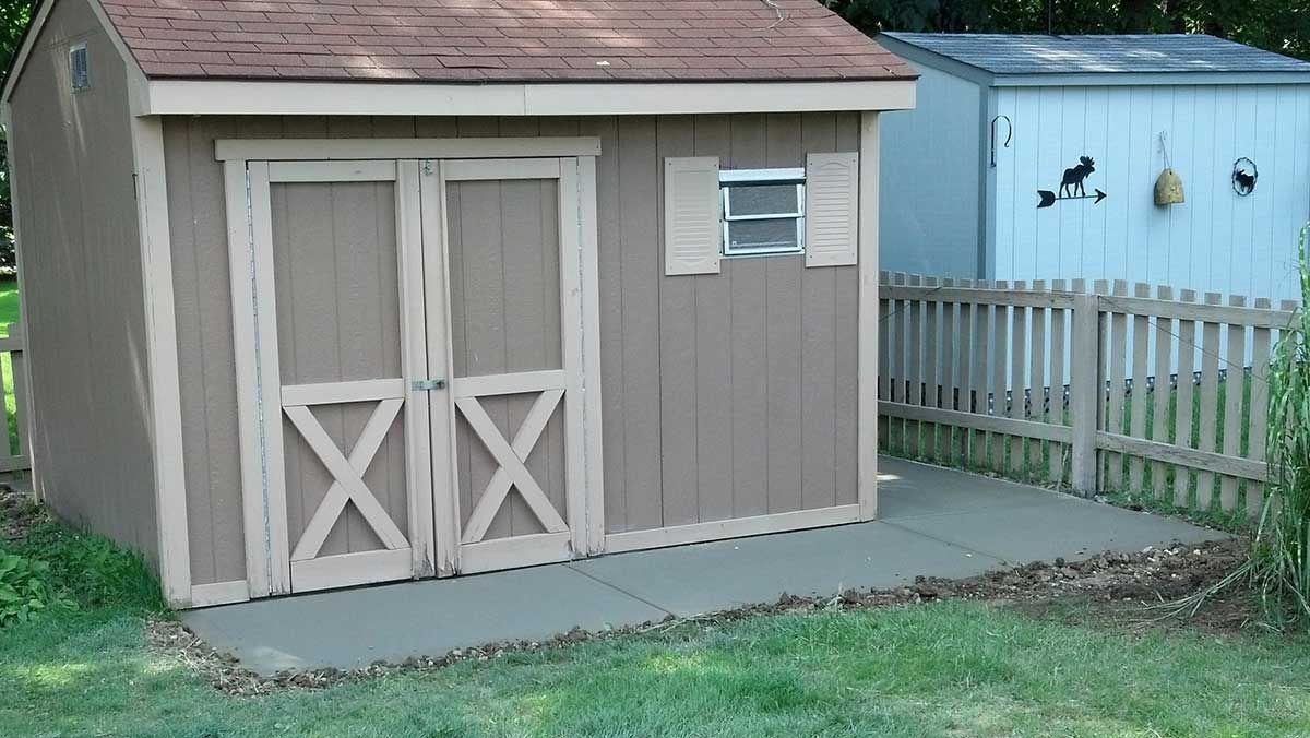 A small shed with a fence in front of it.