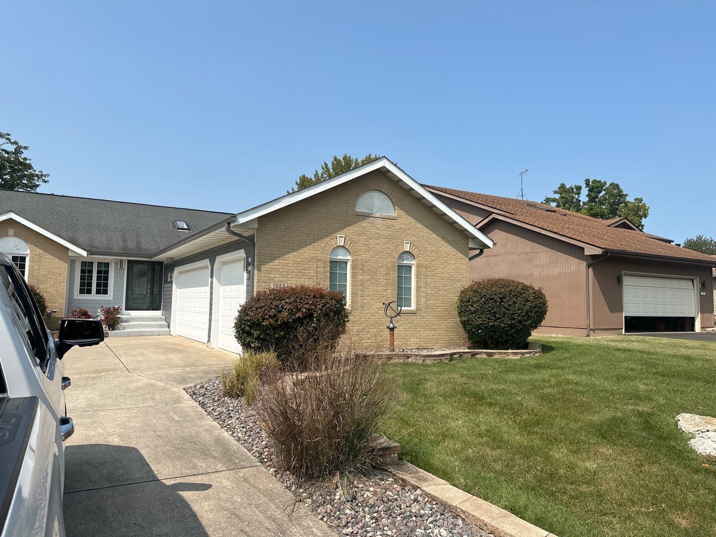 A car is parked in front of a brick house.