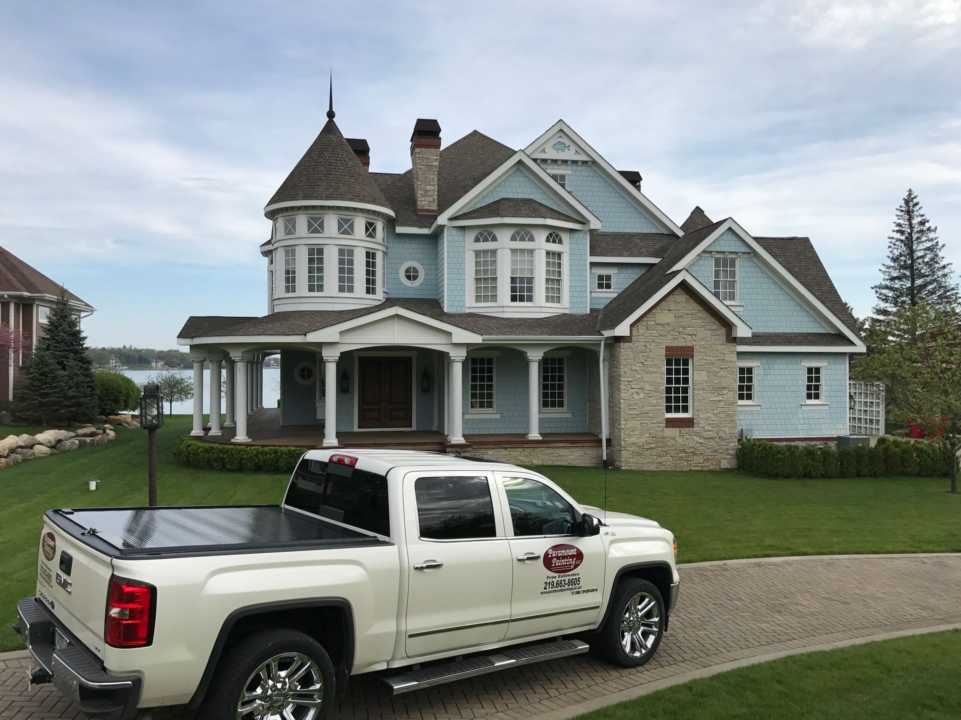 A white truck is parked in front of a large house.