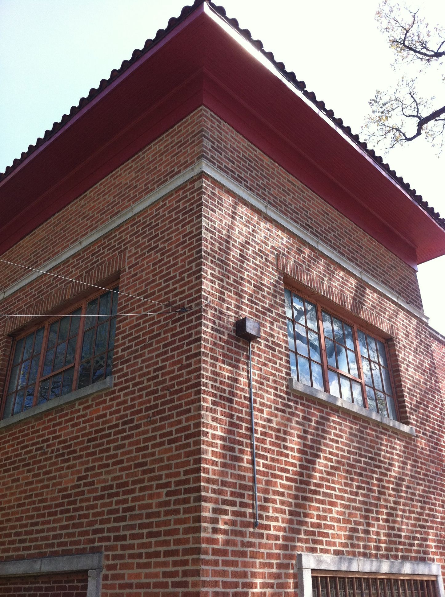 A brick building with a red roof and a lot of windows