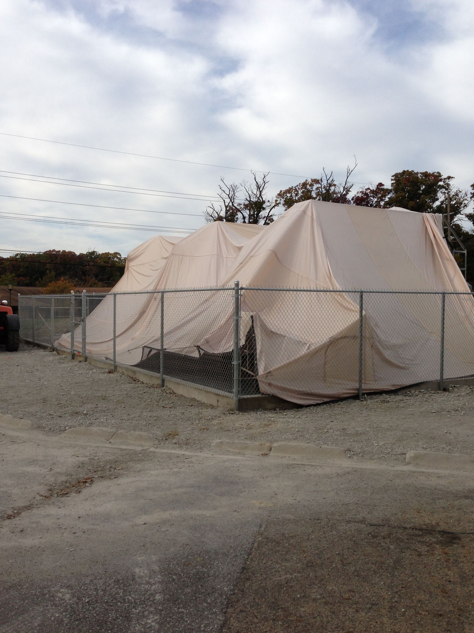 A large white tent is behind a chain link fence