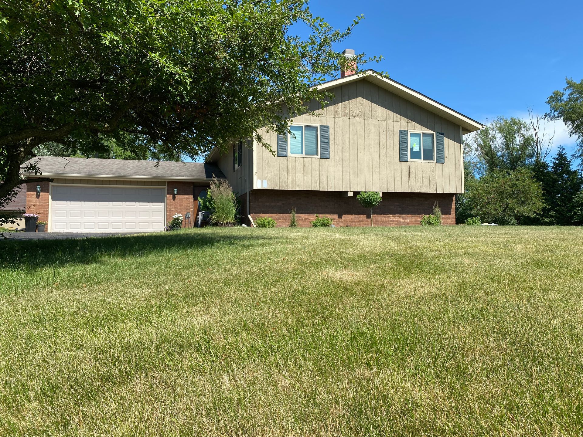 A house with a garage and a tree in front of it
