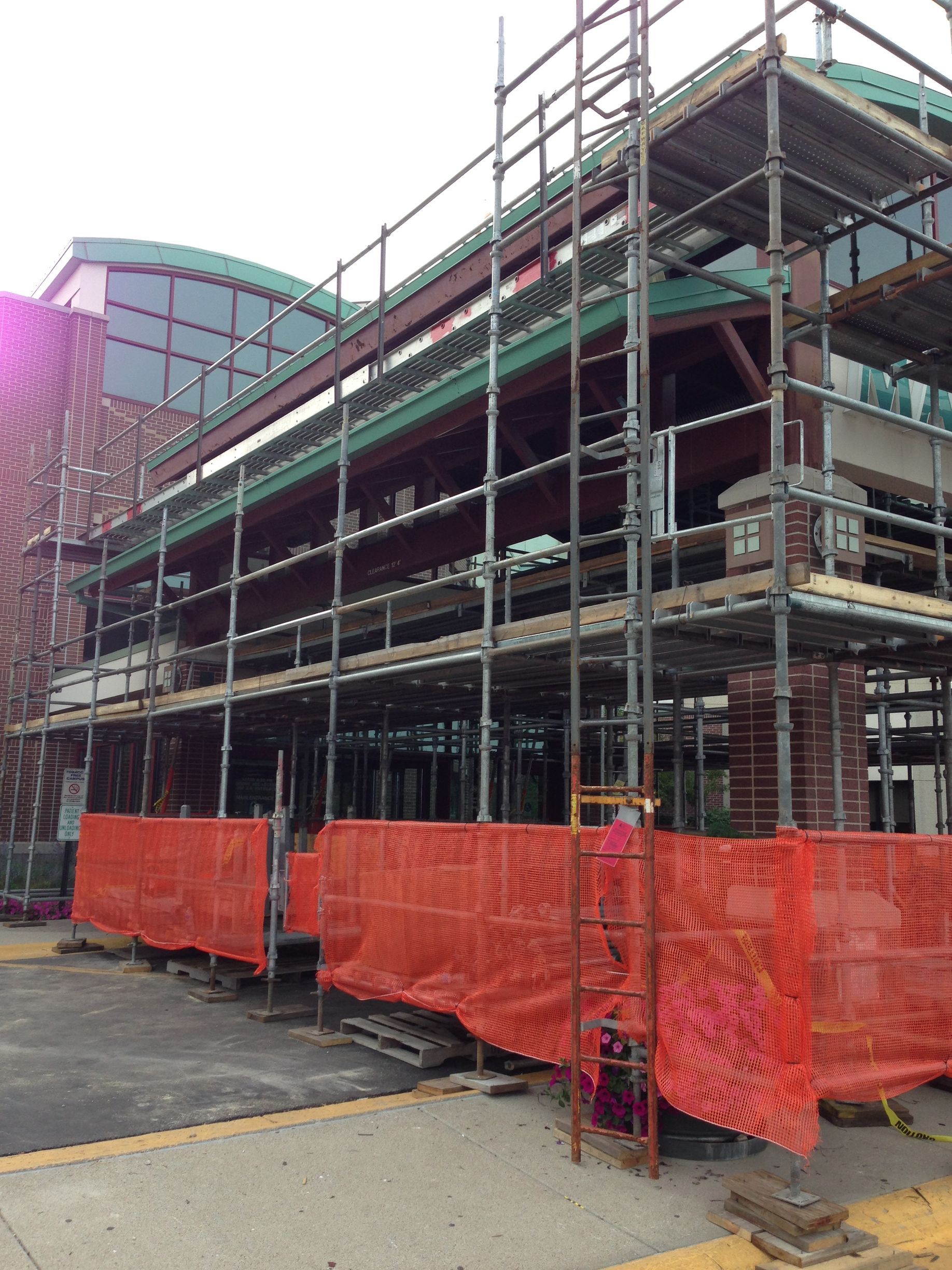A building under construction with scaffolding and orange barriers