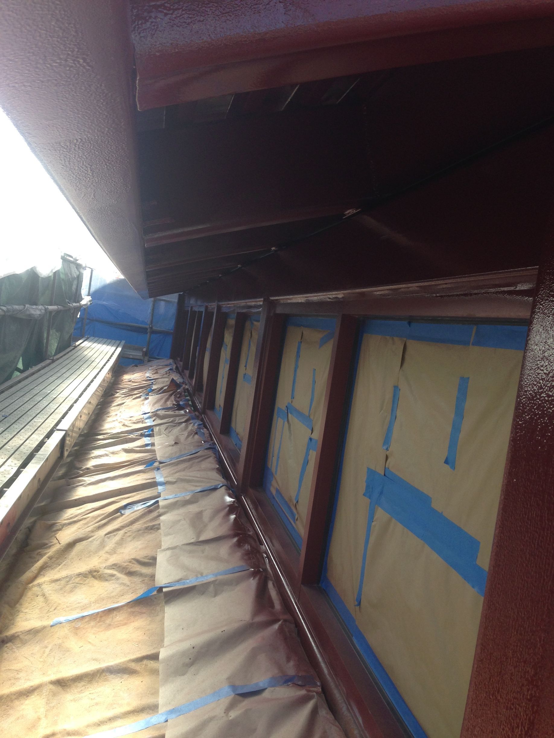 The roof of a building is being painted with a blue tape.