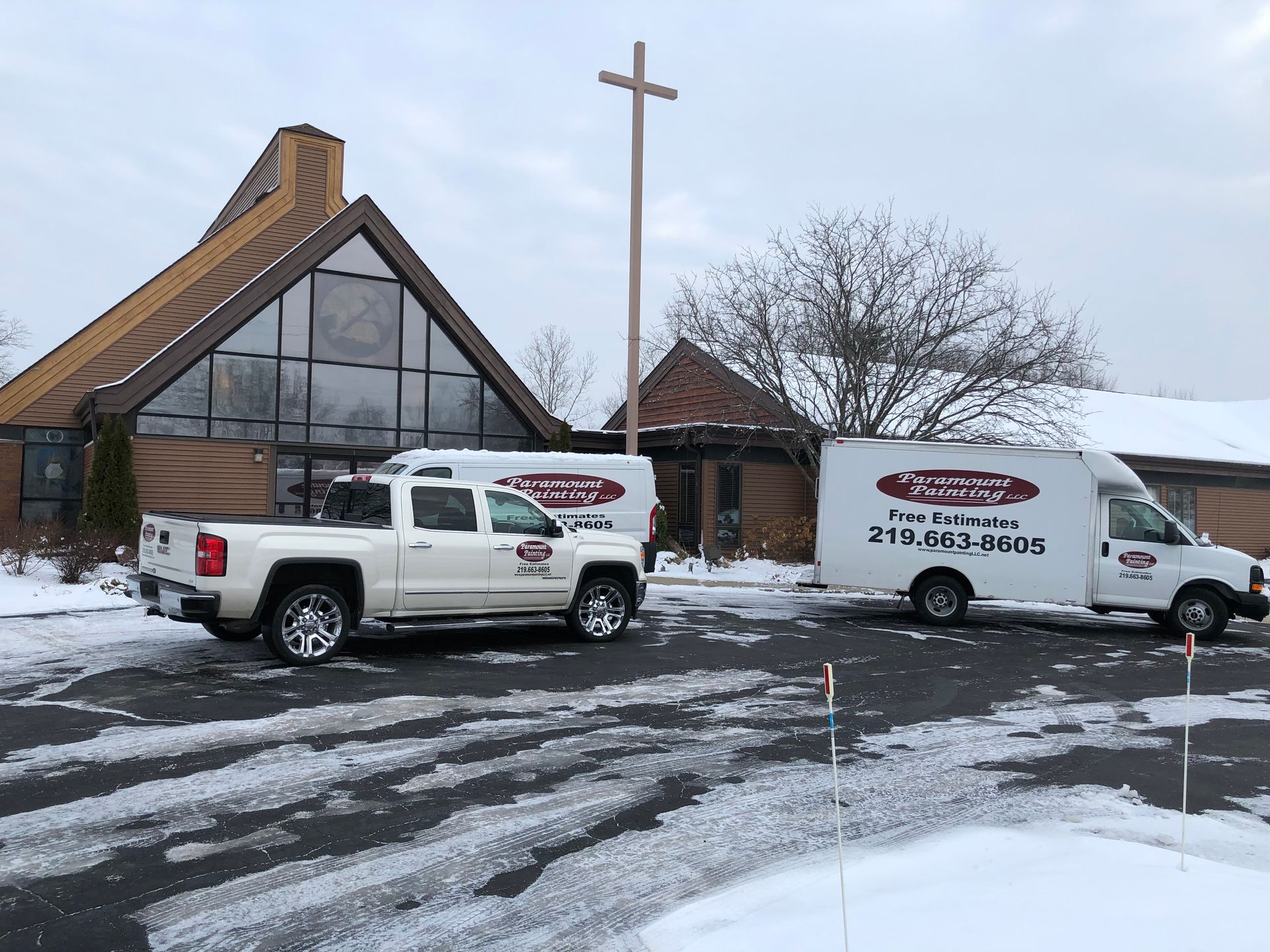 Two trucks are parked in front of a church in the snow.