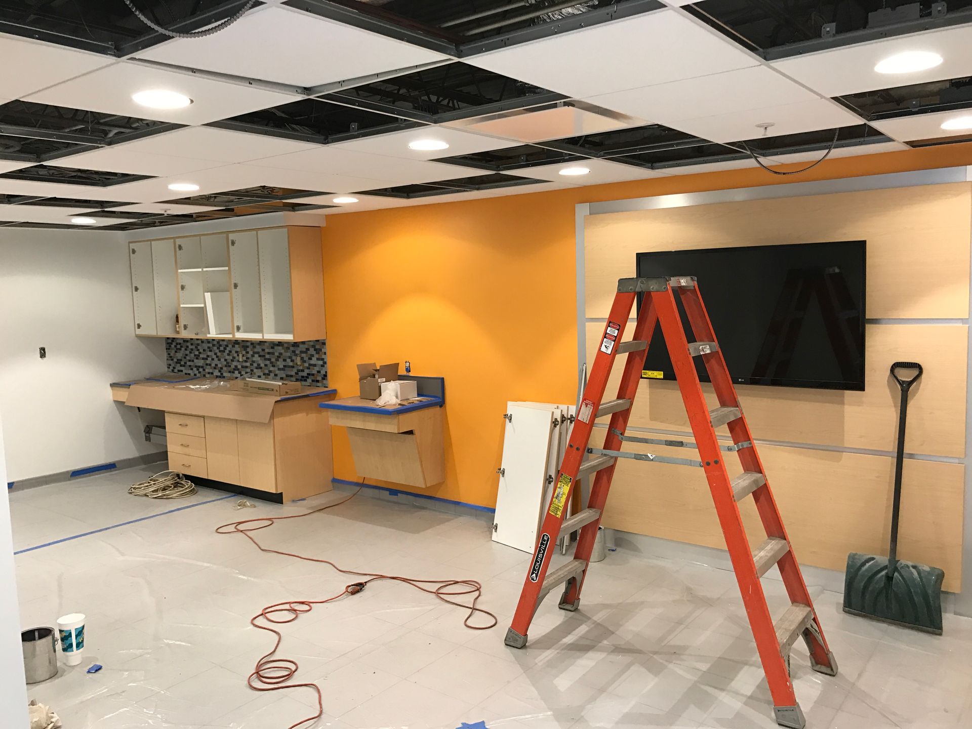 A room with a ladder and a television on the wall.