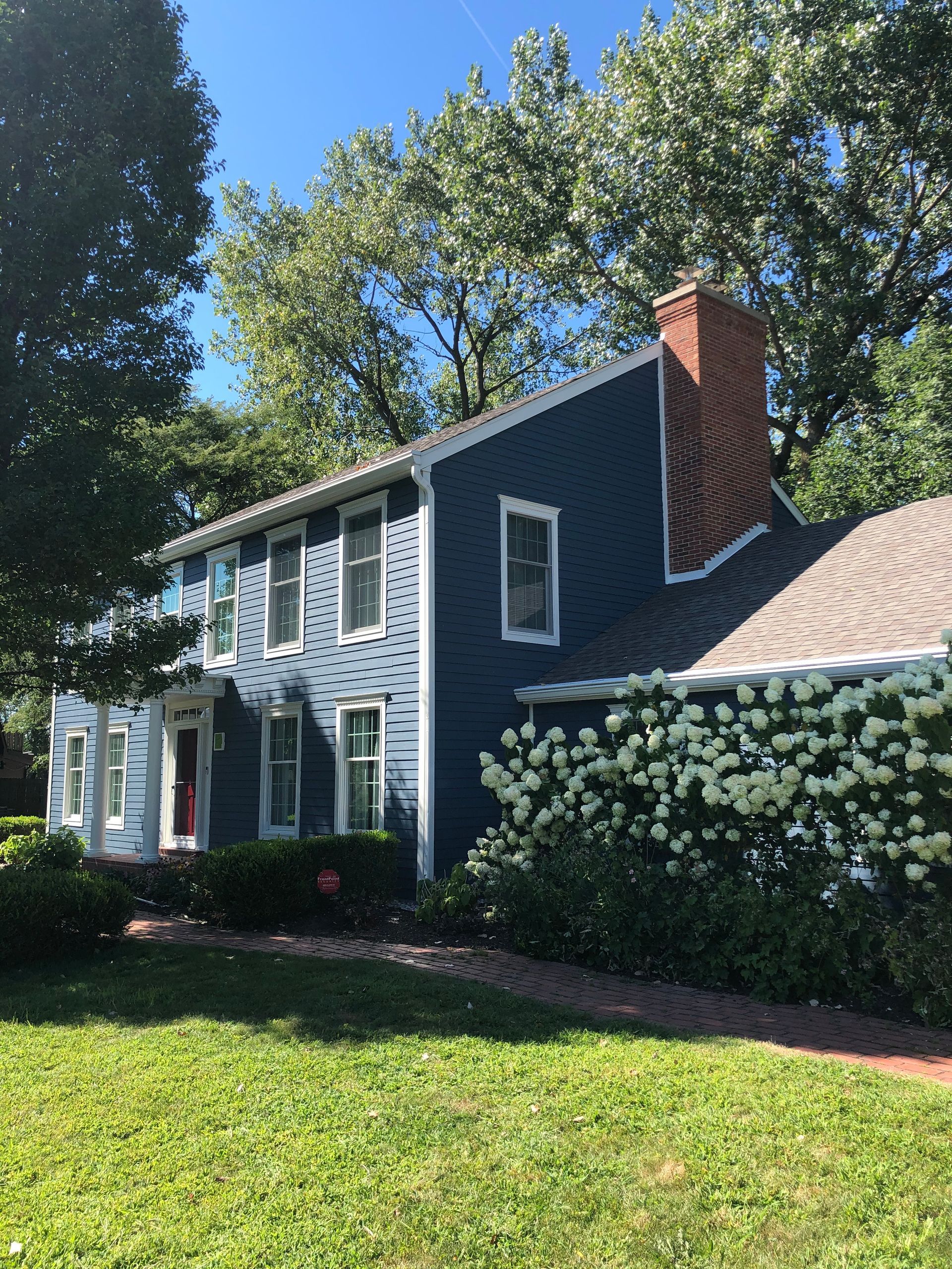 A blue house with white trim and a red chimney