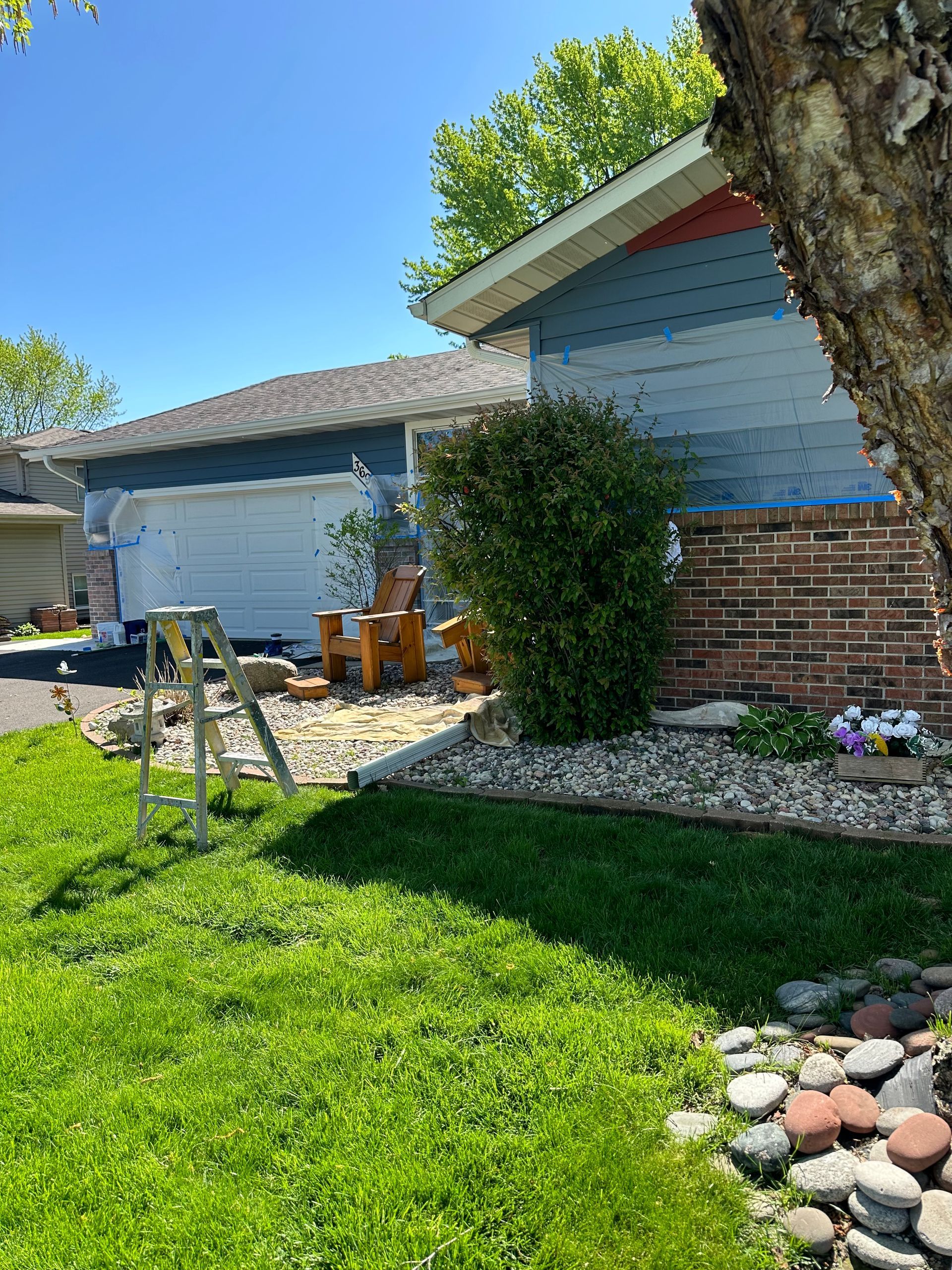 A ladder is sitting in the grass in front of a house.